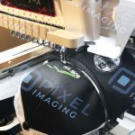 Custom-embroidered baseball cap hat being embroidered on an embroidery machine.